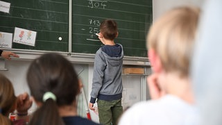 Schüler einer Grundschüler arbeiten in einem Klassenzimmer an einer Mathematikaufgabe. 