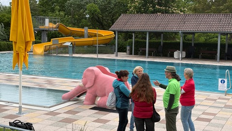 Freibadverwalter Andreas Gölz steht mit Ehrenamtlichen und Badebesuchern vor dem Schwimmbecken des ASV-Freibads Botnang.