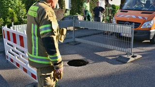 ein Loch in einer Straße in Korntal-Münchingen wird gerade von Einsatzkräften abgesperrt.
