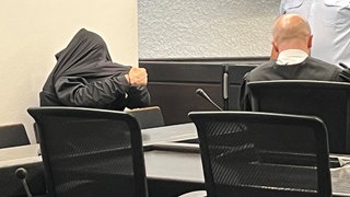 Angeklagter im Kofferleichen-Prozess zieht sich im Gerichtssaal Jacke über den Kopf.