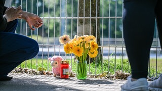 Eine Frau legt Blumen nieder, nachdem ein lebloses Kind in einem Auto gefunden wurde.