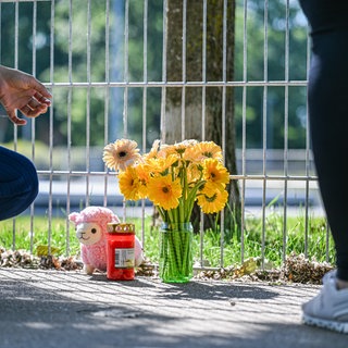 Eine Frau legt Blumen nieder, nachdem ein lebloses Kind in einem Auto gefunden wurde.