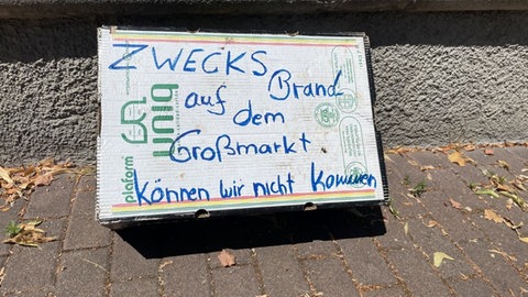 Auf einem Pappschild steht "Zwecks Brand auf dem Großmarkt können wir nicht kommen". Das Feuer auf dem Großmarkt in Stuttgart hatte am Samstag Auswirkungen auf die Märkte in der Stadt.