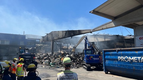 Auf dem Großmarkt in Stuttgart Wangen wird nach dem Feuer Schutt weggebaggert und es qualmt noch. Die Nachlöscharbeiten werden wohl noch bis in den Abend dauern.