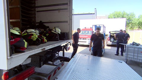 Feuerwehrleute stehen neben einem Lastwagen, der ihre Dienstkleidung gebracht hat.
