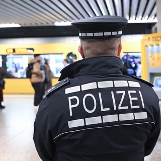 Polizist steht mit Rücken zur Kamera an Stadtbahnhaltestelle Charlottenplatz