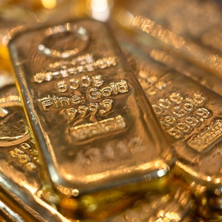 Goldbarren liegen in einem Tresor auf einem Tisch.