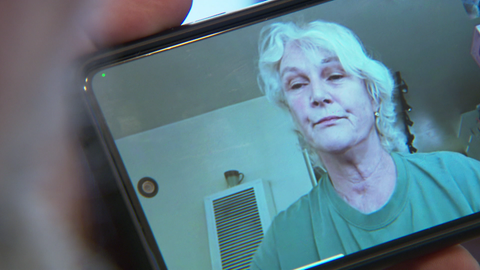 Mann mit längerem Berg sitzt neben vielen Blättern am Schreibtisch.