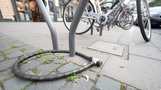 Ein Fahrradschloss hängt ohne Fahrrad an einem Fahrradständer.