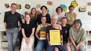 Die Mitglieder der AG "Bunte Uschis" sind aktuelle Schülerinnen, ein Transmann, der früher auf der Freiburger Mädchenschule war, ein Lehrer und eine Lehrerin. Die AG hat einen Preis für ihr Engagement für queere Themen gewonnen.