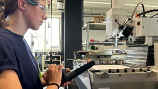 Praktikantin Rebecca Mügge arbeitet konzentriert an einer Maschine des Getriebeherstellers. 