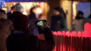 Eine Frau fotografiert ein Haus  - auch im kleinen Turckheim herrscht Weihnachtsstimmung beim Weihnachtsmarkt 