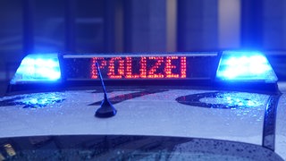 Der Schriftzug "Polizei" ist neben dem Blaulicht auf dem Dach eines Polizeiautos zu lesen.