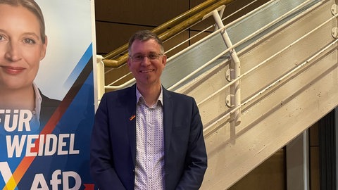 Der AfD-Kandidat des Wahlkreises Emmendingen-Lahr neben einem Wahlplakat der Kanzler-Kandidatin Alice Weidel.