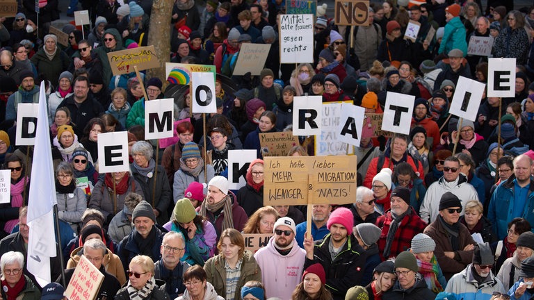 Ihr Anliegen ist nicht zu übersehen: In Lörrach sind mehr als 2.000 Menschen für Demokratie auf die Straße gegangen. Sie halten die Buchstaben für "Demokratie" hoch.