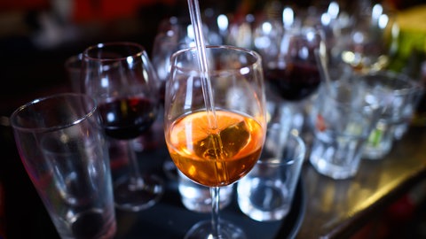 Ein Glas mit orangener Flüssigkeit vor leeren Gläsern auf einer Theke - in Murg wurde eine Fasnachtsfete abgeblasen, nachdem bei mehreren Gästen der Verdacht auf Einnahme von K.O.-Tropfen bestand. 