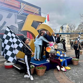 Familie Mack posiert mit den Maskottchen des Europa-Parks vor einer goldenen 50.