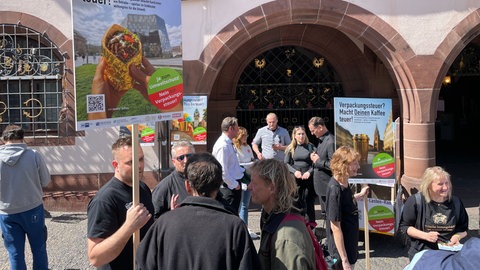 Menschen demonstrieren vor dem Freiburger Rathaus für und gegen die Verpackungssteuer