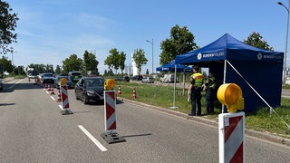 Polizisten haben sich am Straßenrand positioniert, um die vorbeifahrenden Fahrzeuge zu kontrollieren