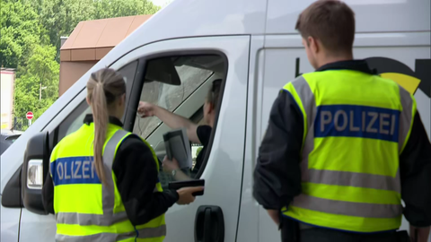 Zwei Polizisten kontrollieren eine Person in einem weißen Transporter