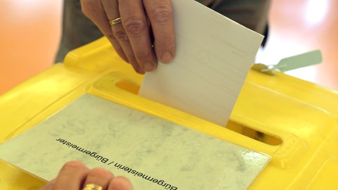 Eine Person wirft ihren Stimmzettel in einem Wahllokal ein. Am Sonntag wird in Teningen (Kreis Emmendingen) ein neuer Bürgermeister gewählt. Zwei Kandidaten stehen zur Wahl. 