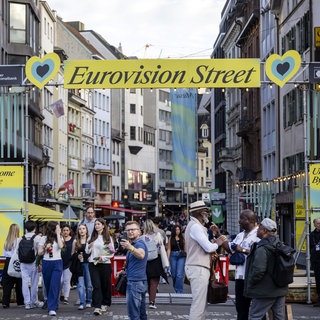 Menschen gehen auf der Eurovisionsstraße im Rahmen des 69. Eurovision Song Contest (ESC). Der ESC findet vom 10. bis 17. Mai 2025 in Basel statt.