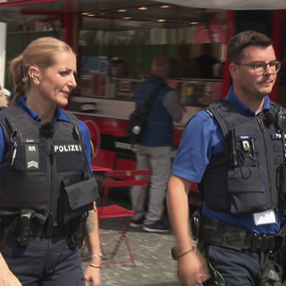 Eine Polizistin und ein Polizist laufen durch die Basler Innenstadt. Sie sind im Einsatz wegen des ESC 2025.
