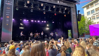 Eine Band steht auf einer Bühne am Barfüsserplatz in Basel. Während des ESC gibt es jeden Tag Live-Konzerte.