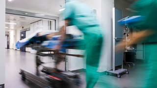 Ärztliches Personal eilt mit einem liegenden Patienten über einen Flur. An den vier Unikliniken in BW fallen Überstunden oft unter den Tisch. Das zeigt eine aktuelle Umfrage.