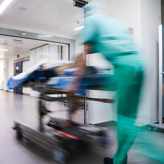 Ärztliches Personal eilt mit einem liegenden Patienten über einen Flur. An den vier Unikliniken in BW fallen Überstunden oft unter den Tisch. Das zeigt eine aktuelle Umfrage.