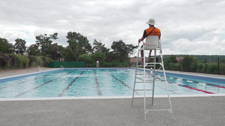 Ein Bademeister sitzt vor einem Schweizer Freibad.