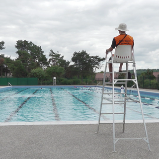 Ein Bademeister sitzt vor einem Schweizer Freibad.