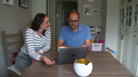 Ein Ehepaar sitzt am Tisch vor dem Computer