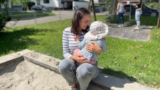 Mutter spielt mit Tochter im Sandkasten auf einem Spielplatz