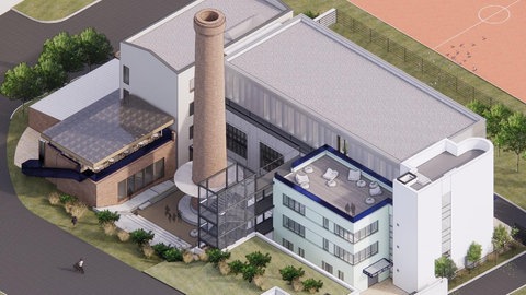 Ein größeres Gebäude. In der Mitte ein Industrieschornstein.