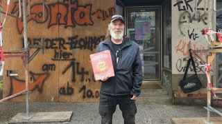 Ein Mann präsentiert eine Straßenzeitung in Freiburg