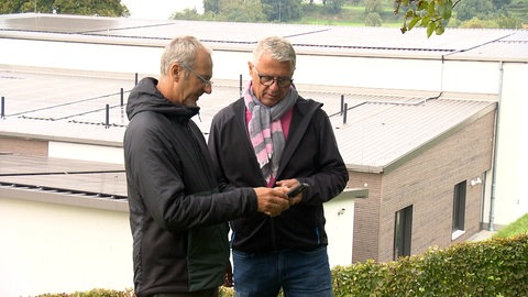 Jörg Bold (links) und Armin Geppert stehen vor einer Photovoltaik-Anlage.