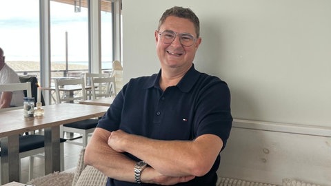 Malte Bayer sitzt in einem Restaurant. 