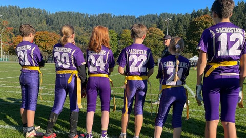 Kinder im lila Football-Dress der Freiburg Sacristans stehen aufgereiht am Spielfeldrand