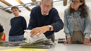 Ein Wahlhelfer blättert durch Stimmzettel des ersten Wahlgangs der Bürgermeisterwahl in Staufen 2025.