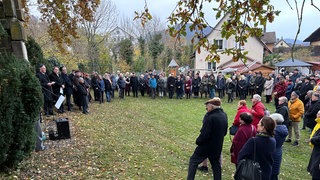 Viele Menschen stehen auf einem Jüdischen Friedhof