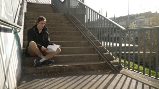 Ein junger Mann sitzt auf Treppenstufen.
