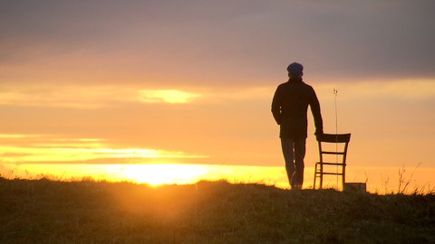 Ein Mann schaut in den Sonnenuntergang