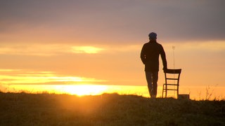 Ein Mann schaut in den Sonnenuntergang