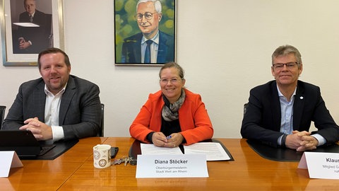 Streit abgewendet - Energieunternehmen arbeiten in Weil am Rhein zusammen - drei Menschen an einem Tisch 