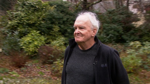 Ein Mann steht in einem Garten.