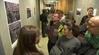 Foto-Ausstellung im Droste-Hülshoff Gymnasium in Freiburg. Besucherinnen und Besucher betrachten die Bilder.