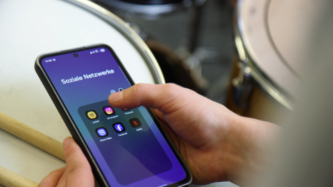 Schüler aus der Bigband schaut auf seinem Handy Social Media an