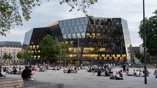 Junge Menschen sitzen auf dem Platz der alten Synagoge vor der Universitätsbibliothek. 