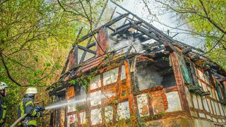 Ein Feuerwehrmann löscht ein brennendes Fachwerkhaus in Offenburg
